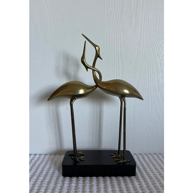 A rare Fredrick Cooper depicting entwined brass cranes on a wooden base.