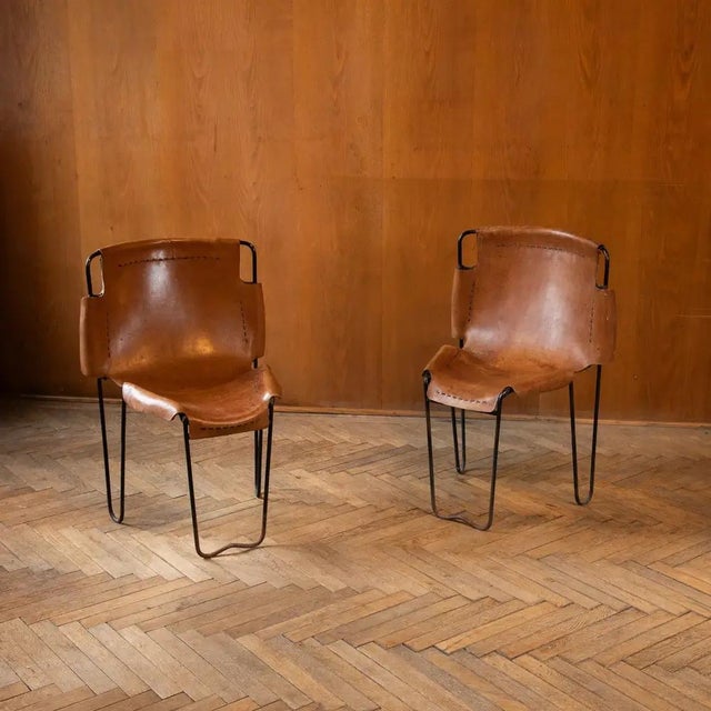 Very rare set of two stacking chairs by Raoul Guys, featuring slender black lacquered wire frames and thick saddle leather...