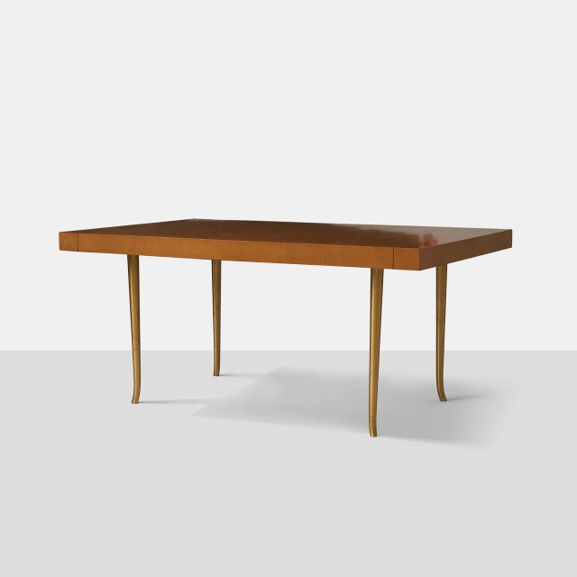 T H Robsjohn-Gibbings Dining Table A dining table in Italian walnut with two end-mounting leaves siting atop four slightly...