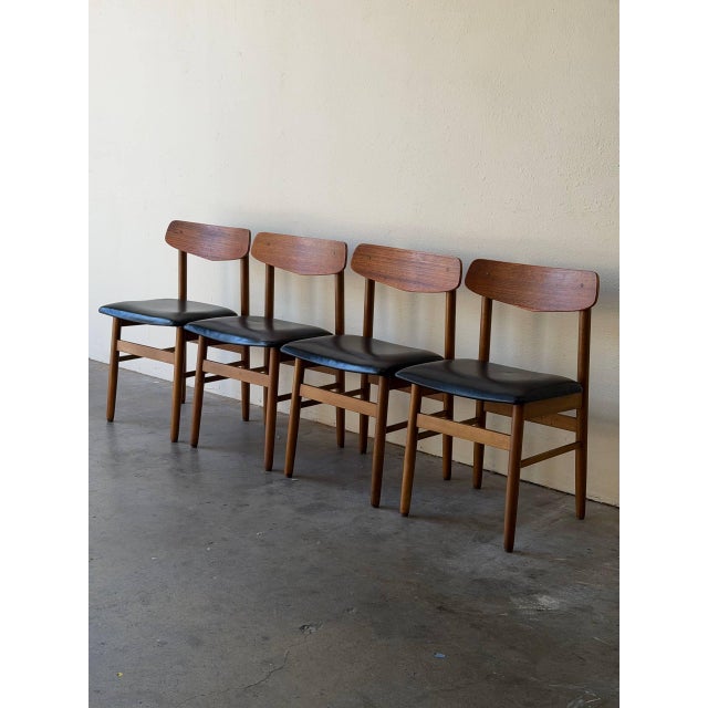 Beautiful set of four vintage Danish dining chairs crafted in solid teak with original black leather seats. These chairs...