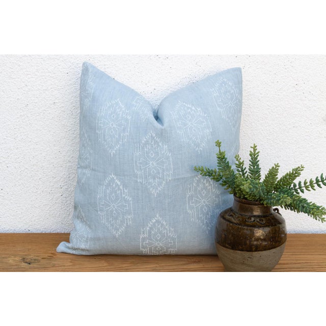 A repeating diamond medallion in soft white ink covers the full face of this pillow, hand block-printed on pale powder-...