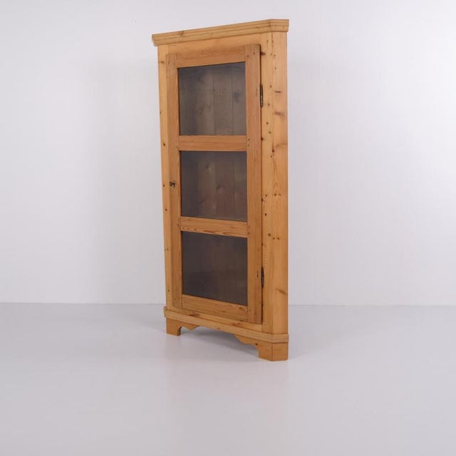 Antique corner cabinet crafted from pine with a glass door and three interior shelves. The cabinet was made in the 1890s...