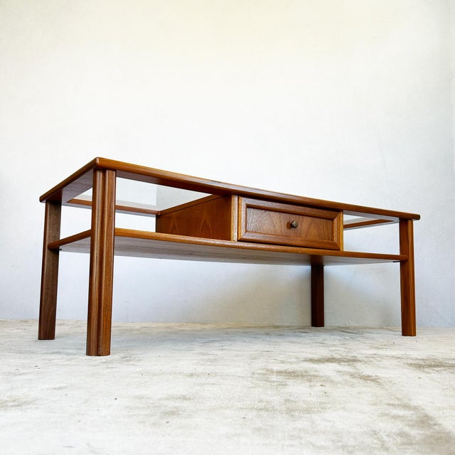 G-Plan coffee table featuring two inset glass panels set into a teak frame with central solid wood section. Single drawer...