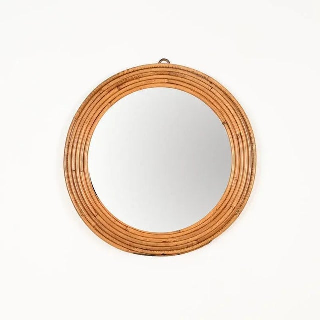 Stunning Mid-Century round mirror fully made of curved rattan. This elegant and unique organic piece was produced by Vivai...