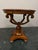 Elegant vintage round center table featuring burl wood veneer, a decorative inlaid top, and a Regency-style pedestal base....