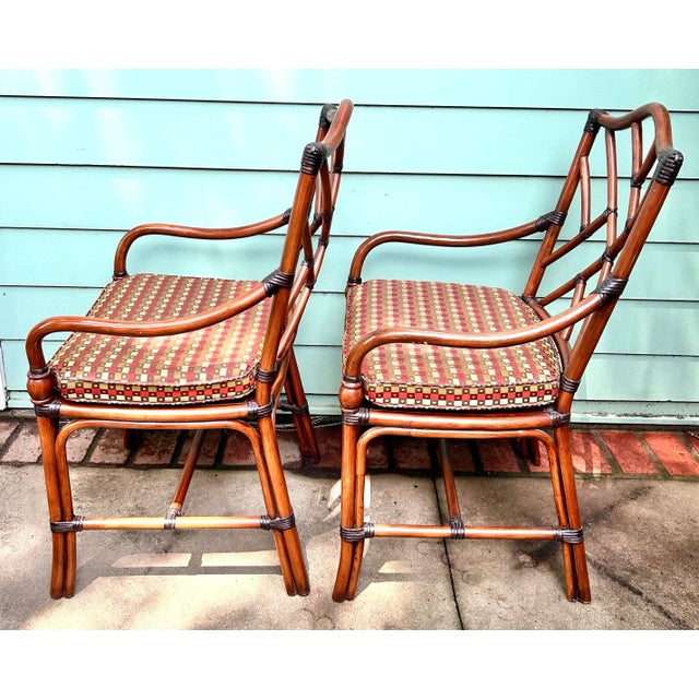 A classic pair of 1980s Chinese Chippendale-style armchairs featuring faux bamboo frames, lattice backs, and original cane...