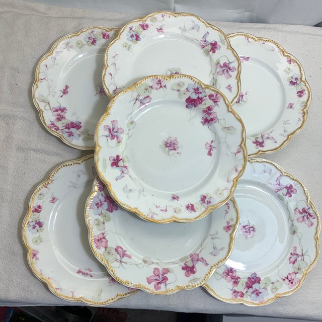 These antique Haviland Limoges porcelain plates feature a scalloped gold-gilt rim and a delicate pink and purple floral...