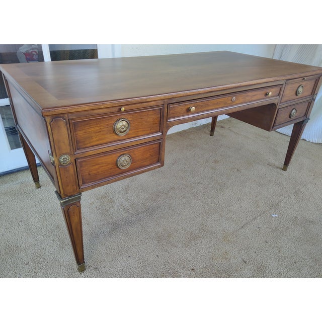 Restored French Style partner's desk by Baker Furniture with five drawers and three pullouts,. Features brass accents. The...