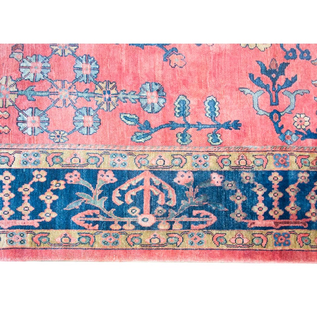 An exquisite antique Persian Sarouk Mahal rug, hand-woven circa 1920 with wool and natural dyes. The expansive coral-red...