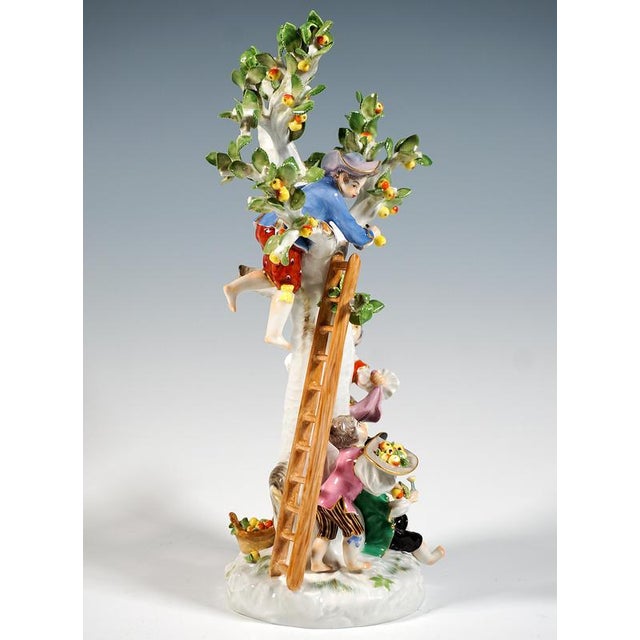 Elaborately crafted porcelain group: a young gardener and three boys harvesting apples, dressed in rural rococo robes with...