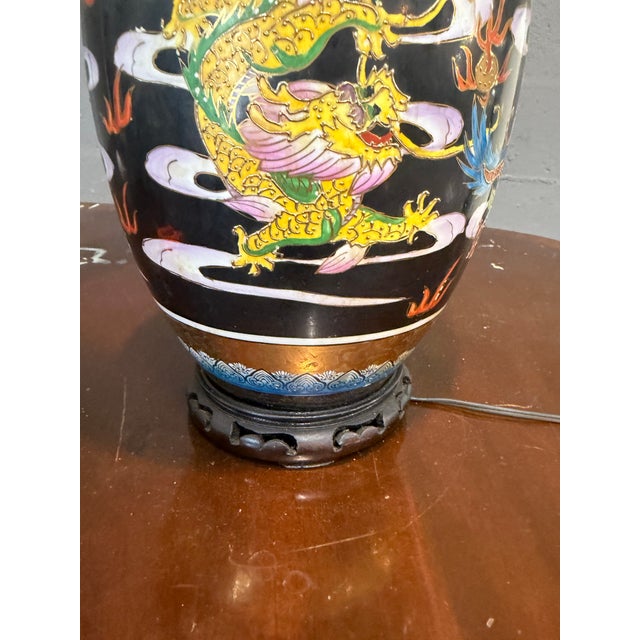 Famille noir, vintage table lamp featuring a hand-painted black ceramic vase base with a colorful dragon motif on a carved...