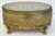 Vintage gilded brass Ormolu jewelry box with beveled glass top with a gold velvet lining to interior. Frame features...