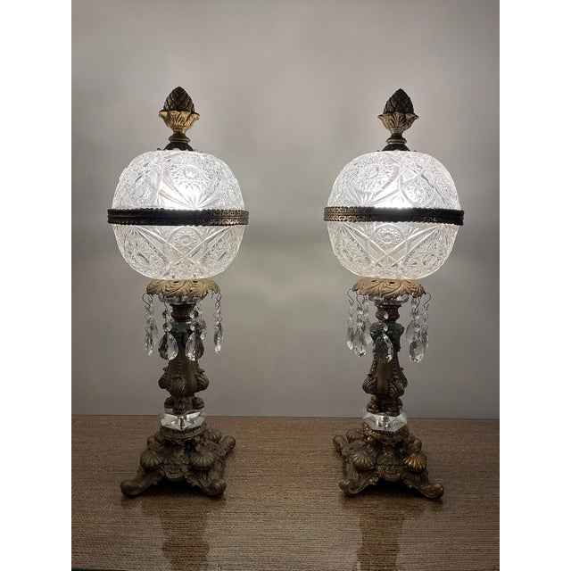 Elegant pair of vintage table lamps featuring brilliant cut crystal-style globe shades, ornate gilt metal bases, faceted...