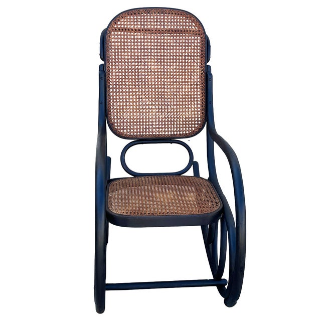 Turn of the century bent oak rocking chair w/woven wicker seat features an elegant, sculptural frame crafted from dark-...