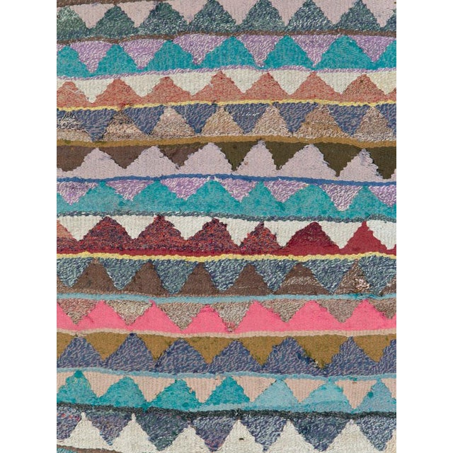 This Mid-20th century Persian flatweave kilim is defined by a richly layered field of horizontal stripes that create a...