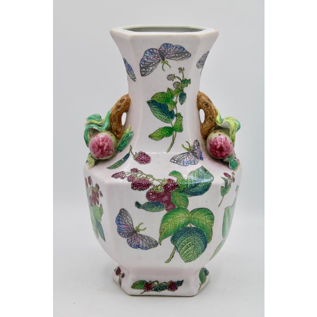 A lovely Asian ceramic vase depicting flora, fauna, and butterflies. The pomegranate handles are a charming touch.