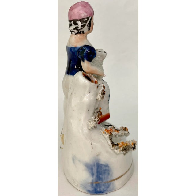 This antique Staffordshire spill vase, featuring a shepherdess with a lamb, is a classic example of 19th-century English...