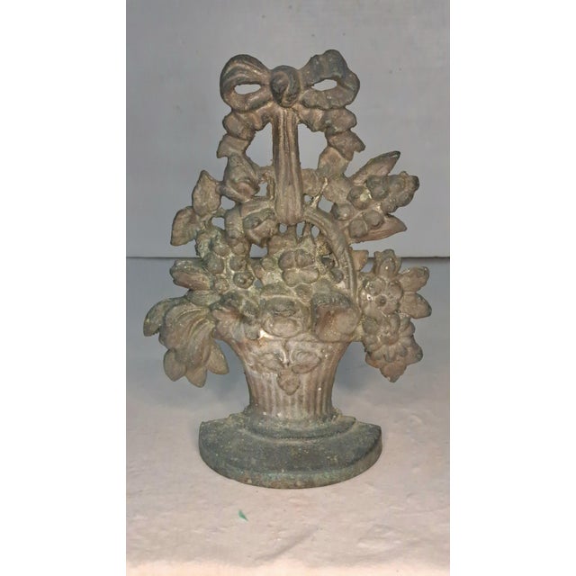 An ornate antique solid cast brass doorstop in the form of a lush floral basket or urn. The openwork design features a...
