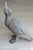 A cast zinc duck with head raised and beak lifted, finely detailed with layered feather texture and webbed feet....