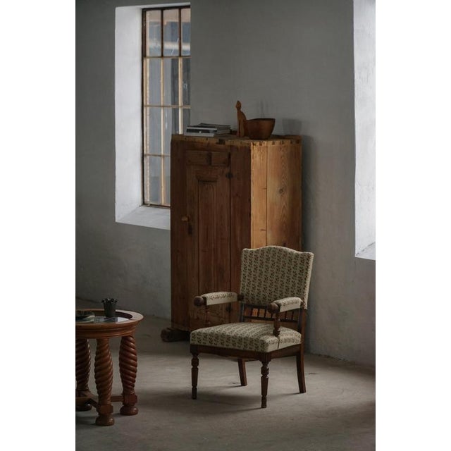 A charming early 20th-century armchair, characterized by its elegant turned wooden frame and softly balanced proportions....