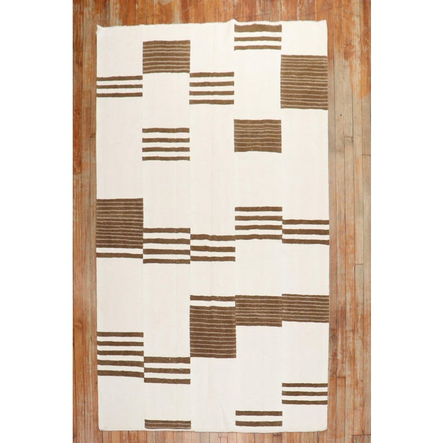 Intermediate-size Modern Turkish Kilim in ivory and brown made from recycled cotton and goat hair material giving it an...