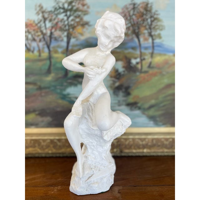 This vintage plaster sculpture presents a seated nude female figure in a delicate, introspective pose, her arms crossing...