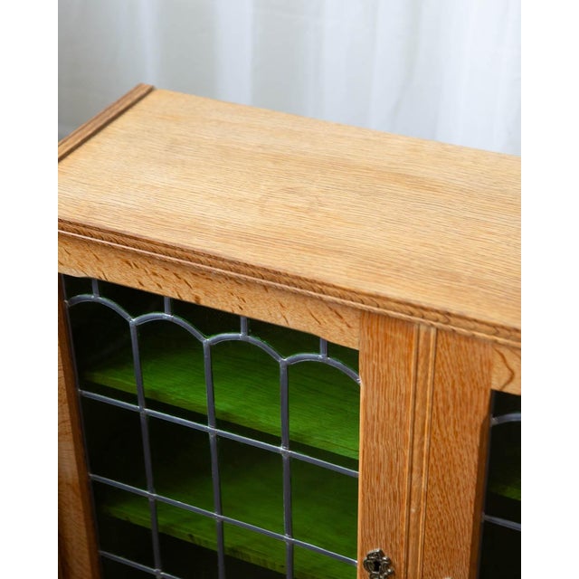 A Danish oak cabinet in the style of Henning Kjærnulf, distinguished by stained glass door panels — a detail that brings...