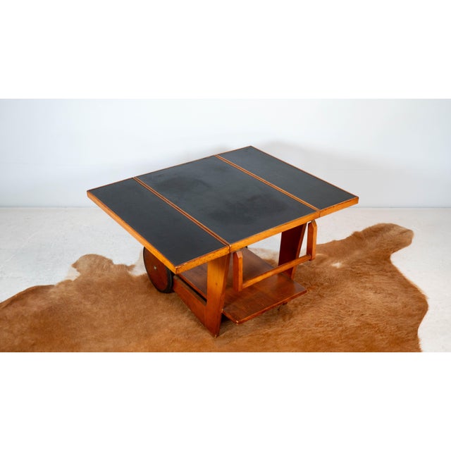 Unique Art Deco wooden bar cart, circa 1950s. Reminiscent of Alvar Aalto's aesthetics. Dual folding table top with spring...