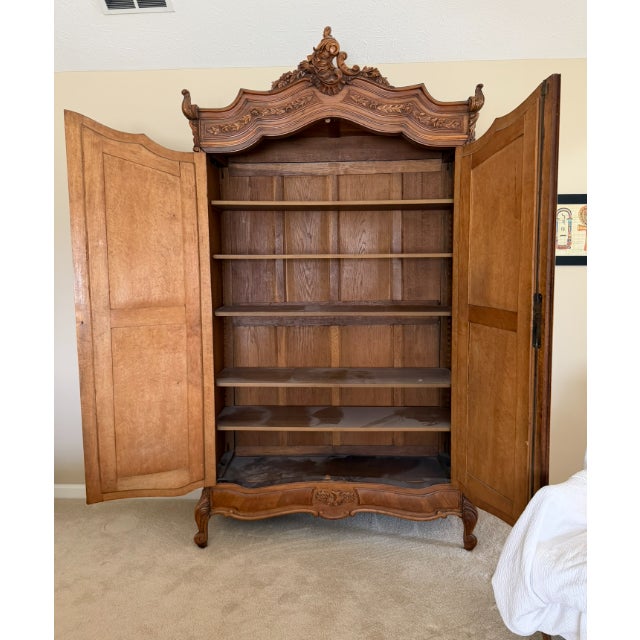 French Louis XV style armoire crafted in hand-carved walnut with beveled mirror doors. The case features cabriole legs...