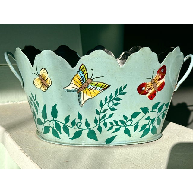 A charming vintage toleware cachepot with a rare teal‑turquoise painted ground and hand‑painted butterfly and vine motifs....