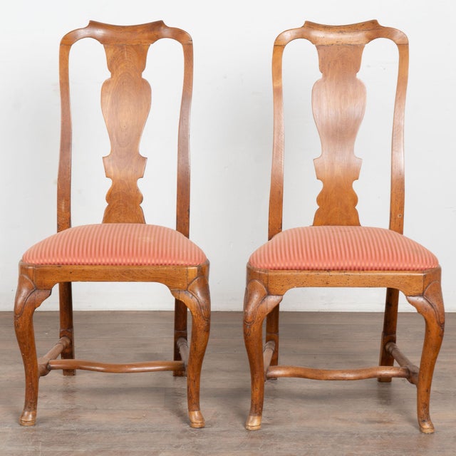 Late 18th century Danish Rococo side chairs, crafted in oak. The chairs feature graceful cabriolet legs joined by a turned...