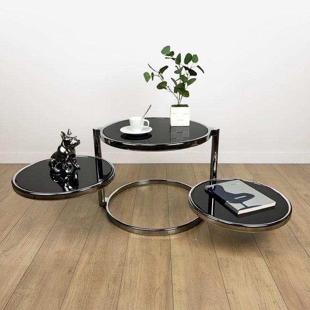 This stunning sculptural coffee table with three rotating black glass tops is designed to be both functional and visually...