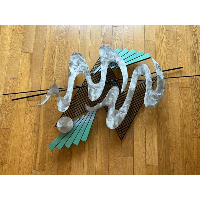 Unique memphis style wall art made with metal and has the metallic finishes on each of the following shapes: the two curvy...