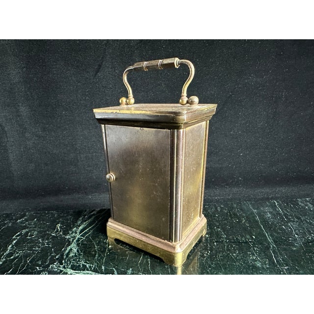 Tiffany & Co. brass carriage clock with beveled glass side panels and a top carry handle. White dial with black Roman...