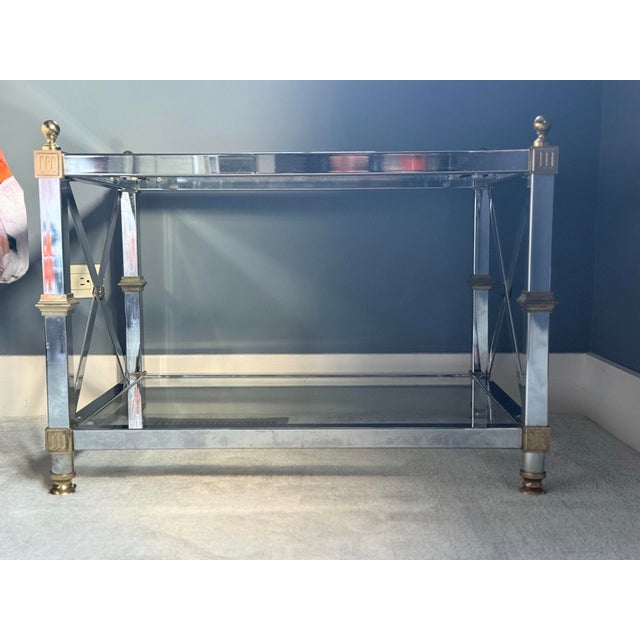Neoclassical chrome, brass & glass low rectangular table. The glass plate held by a cage form base with X supports, brass...