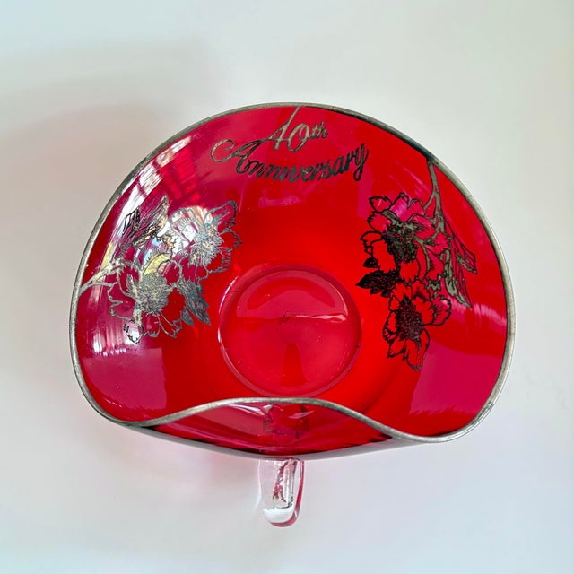 A wonderful piece of vintage celebration glass—this ruby red anniversary heart-shaped bowl with handle is decorated with a...