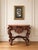 A beautifully carved antique walnut console table with a richly sculptural presence. The piece features a shaped top, deep...