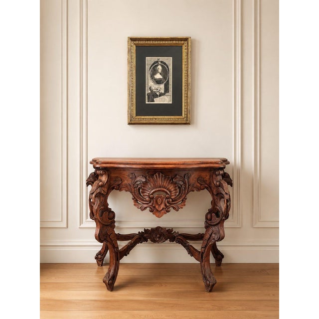 A beautifully carved antique walnut console table with a richly sculptural presence. The piece features a shaped top, deep...