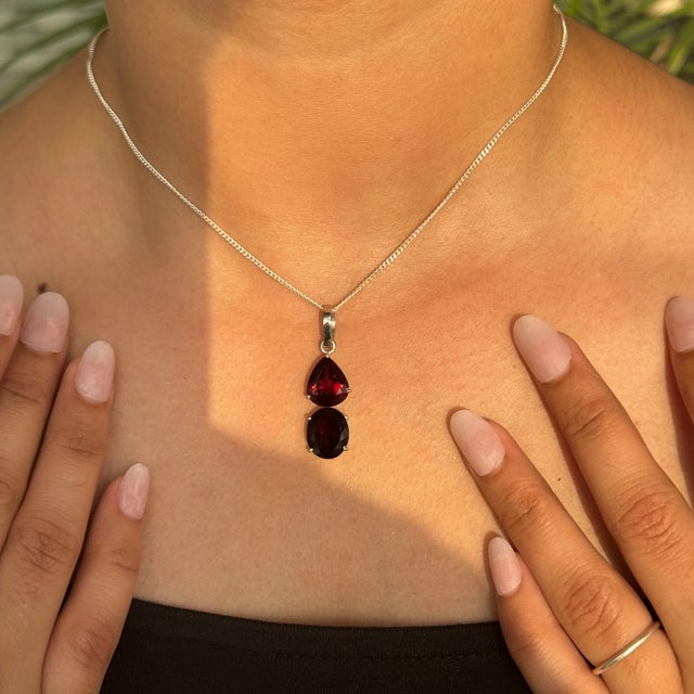 Handcrafted in 925 sterling silver, this pendant showcases the rich allure of two natural garnets in a refined dual-stone...