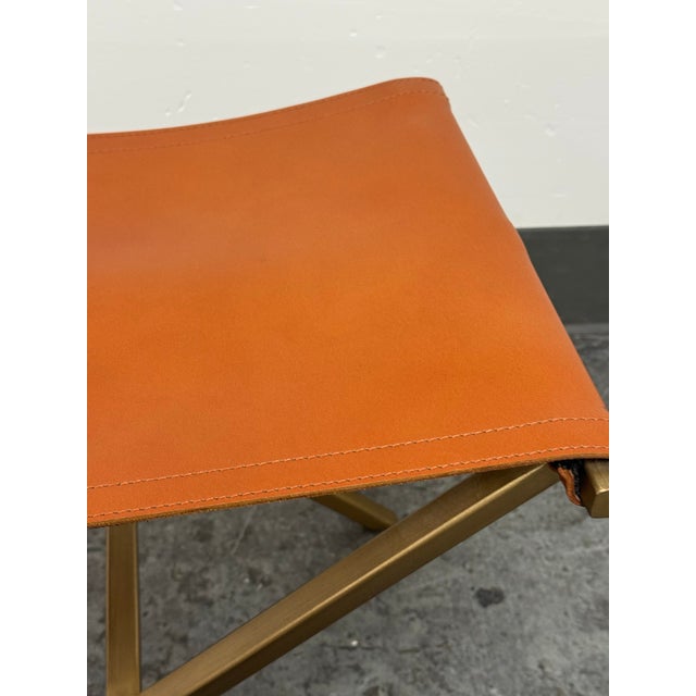 Design Plus Gallery presents the Directors Stool from CB2. This stool has an orange leather sling seat with stitched edge...