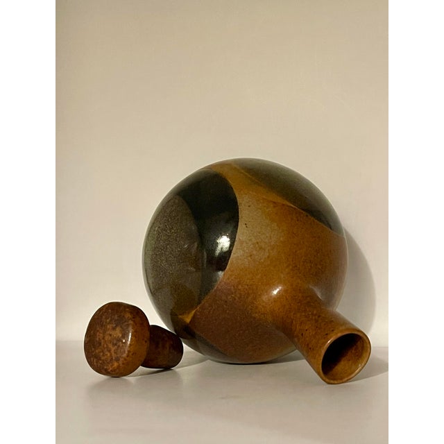 A classic mid 20th century California decanter featuring a pattern of overlapping circles of browns, grays and black on...