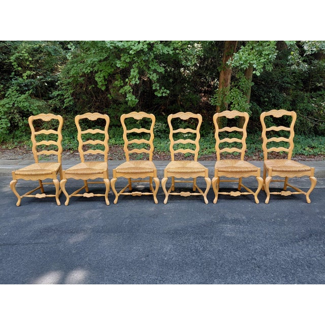 Charming set of six French-made dining chairs featuring carved floral details, shaped ladder backs, cabriole legs and...