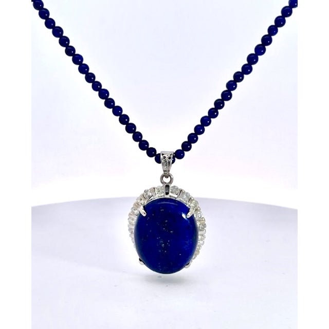 This stunning necklace features a striking lapis lazuli cabochon pendant, showcasing the gemstone's signature deep royal...