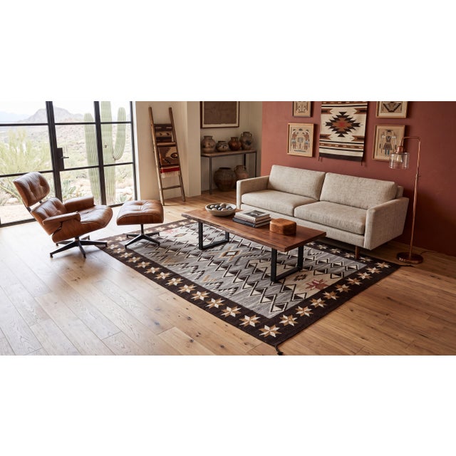 This striking hand-woven wool rug seamlessly marries traditional Navajo-inspired geometric motifs with a sophisticated...