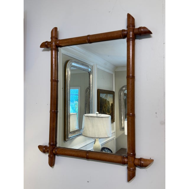 This is a French antique faux-bamboo wall mirror with a hand-carved wood frame. The frame is wood that has been shaped and...