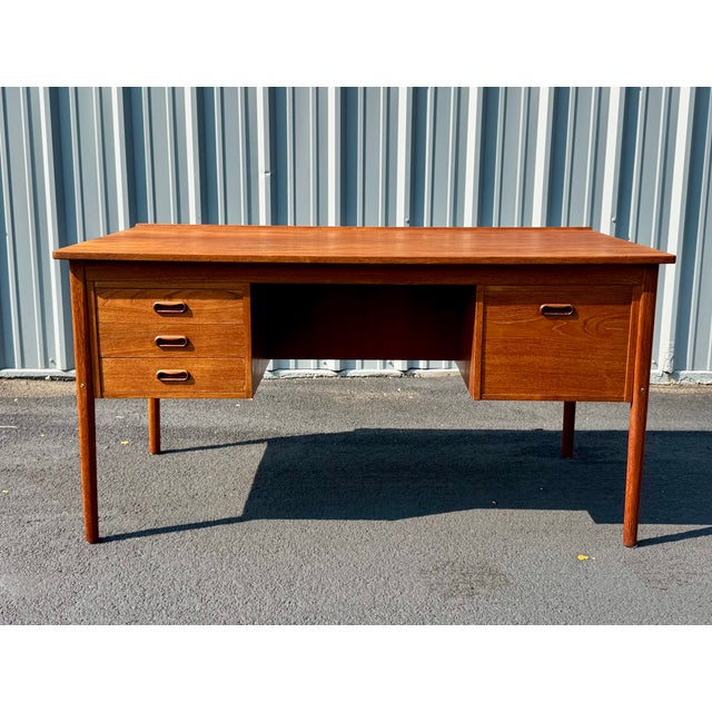 Danish teak desk with four drawers and bookcase on back side. Classic Danish Modern design elements including raised edge...