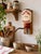 A distinctive vintage French wall-mounted coffee grinder, featuring a cream-glazed ceramic reservoir decorated with a...