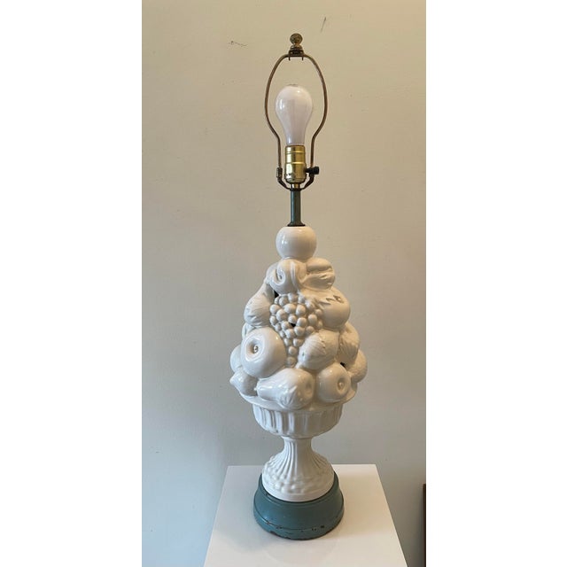 A sculptural 1950s Italian blanc-de-chine porcelain table lamp featuring a dramatic stacked fruit topiary motif. The base...