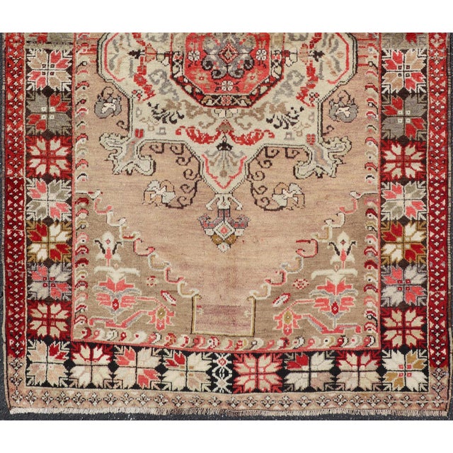 This vintage Turkish Oushak carpet (circa 1940) features a central blossoming medallion flower surrounded with smaller,...