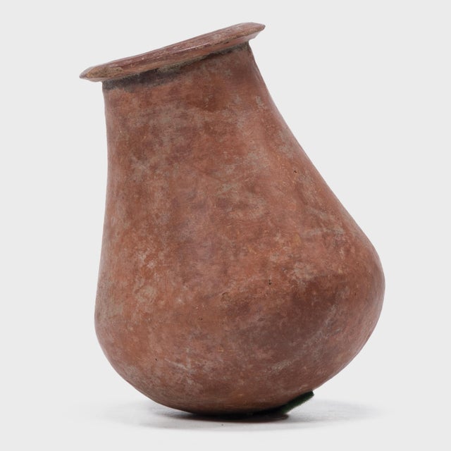 This petite hand-formed vessel bears a richly textured surface of worn red clay slip and dark smoke marks. Likely intended...